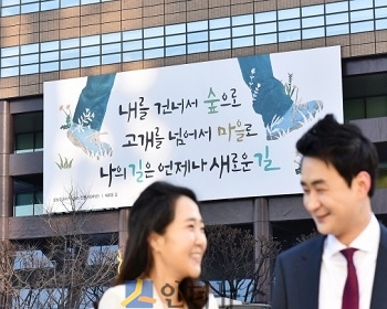 6일 시민들이 교보생명 광화문글판 '봄편'이 내걸린 광화문 교보생명빌딩 주변을 걷고 있다. 이번 문안은 우리나라 대표 민족시인인 윤동주의 시 '새로운 길' 에서 가져왔다.