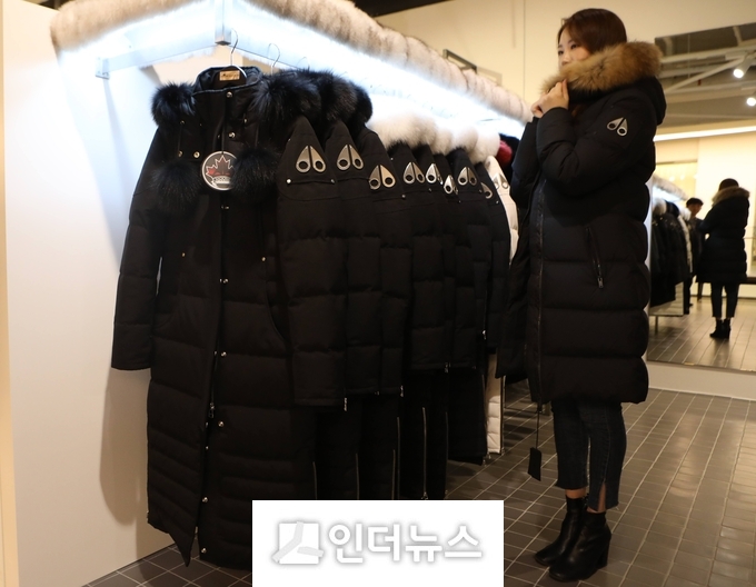 고객이 롯데백화점 프리미엄 패딩존에서 옷을 입어보고 있다. 