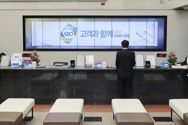 우리은행은 고객 맞춤형 서비스 제공을 위한 '디지털 사이니지'를 도입했다고 10일 밝혔다. 고객들이 디지털 사이니지가 설치된 우리은행 본점영업부에서 업무를 처리하고 있다. Photo @ 우리은행