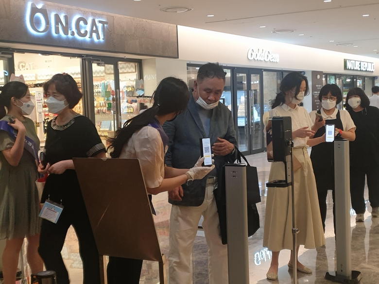  지난 13일, 현대백화점 무역센터점 직원이 출입구에서 고객에게 QR체크인을 안내하는 모습. 사진ㅣ인더뉴스