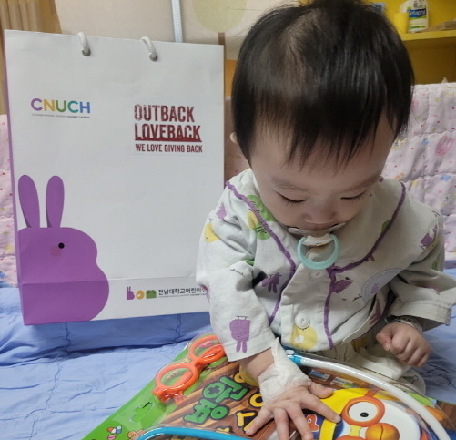 지난 16일 전남대학교 어린이병원에 입원중인 환아가 bhc아웃백의 '러브백 데이'에서 기증한 선물키트를 보고 있다. 사진│bhc아웃백