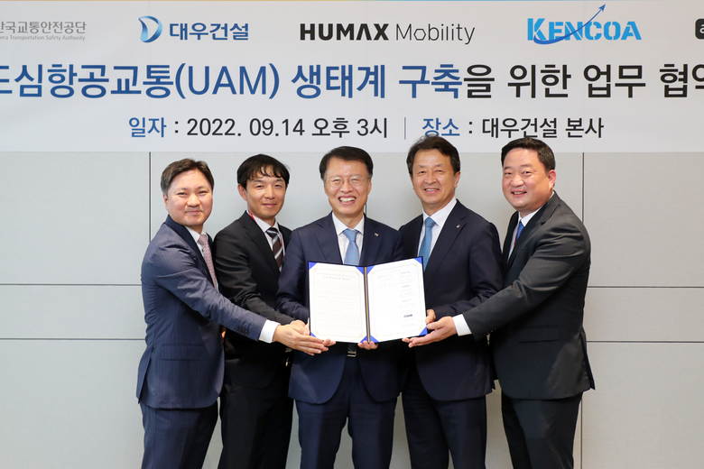 (사진 왼쪽부터) 오영현 휴맥스모빌리티 대표, 전부환 아스트로엑스 대표, 권용복 한국교통안전공단 이사장, 백정완 대우건설 대표이사, 정재한 켄코아에어로스페이스 부사장이 K-UAM 관련 업무협약을 체결한 후 사진촬영에 임하고 있다. 사진ㅣ대우건설