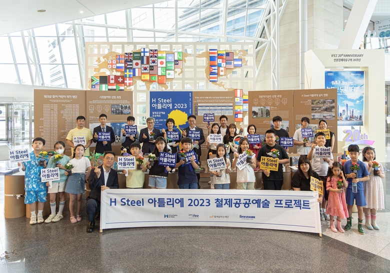 안동일 현대제철 사장(후열 좌측 6번째)과 이행숙 인천시 정무부시장(후열 좌측 10번째), 김진용 인천경제자유구역청장(후열 좌측 4번째), 공모 당선 작가, 지역 아동들이 H-아틀리에 포토월에서 사진촬영에 임하고 있다. 사진ㅣ현대제철