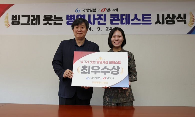 서울 용산구에 위치한 국방홍보원에서 지난 24일 열린 ‘빙그레 웃는 병영사진 콘테스트’의 최우수상 수상자인 이오르난 중위(오른쪽)가 채일 국방홍보원장과 기념 촬영하고 있다. 사진|국방일보